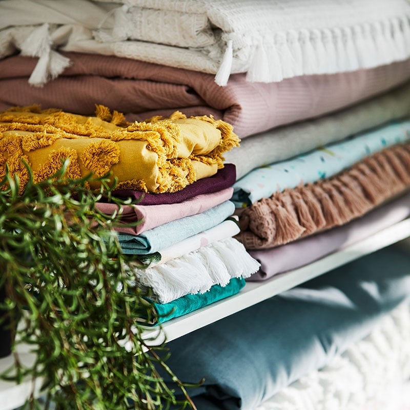 Close up of a shelf with various pattern and coloured quilt covers, throws and sheets