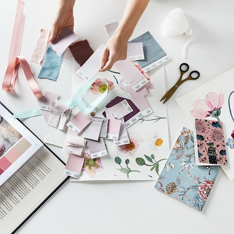 Collage of colour swatches, paper and materials scattered on a table