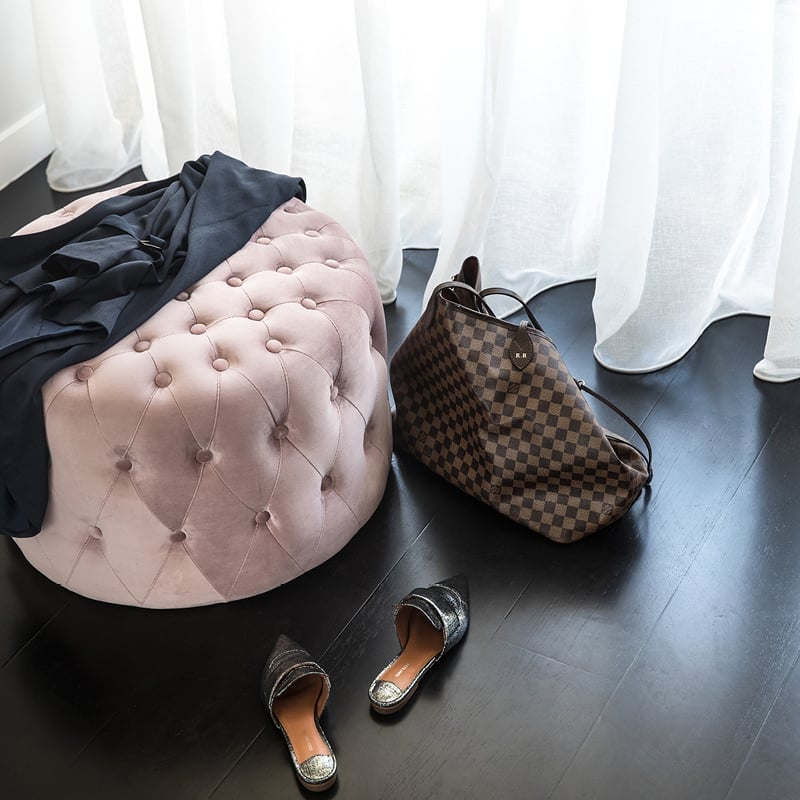 Pale pink velvet poof against a black timber floor.
