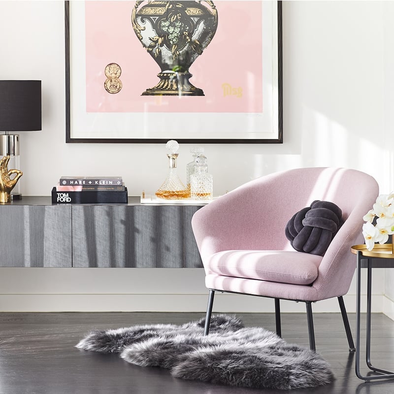 Bedroom corner styled with a pink armchair, and velvet navy blue knotted round cushion.