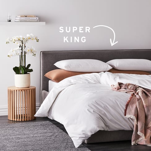 Side-view of bed with white quilt cover and text that reads “Super King” with an arrow pointing to the quilt. 