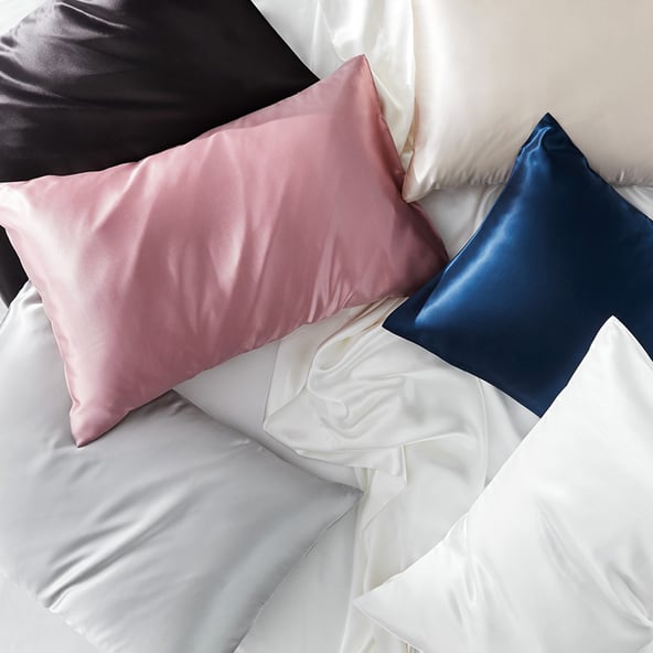 An aerial shot of an assortment of coloured silk pillows and white silk sheet.