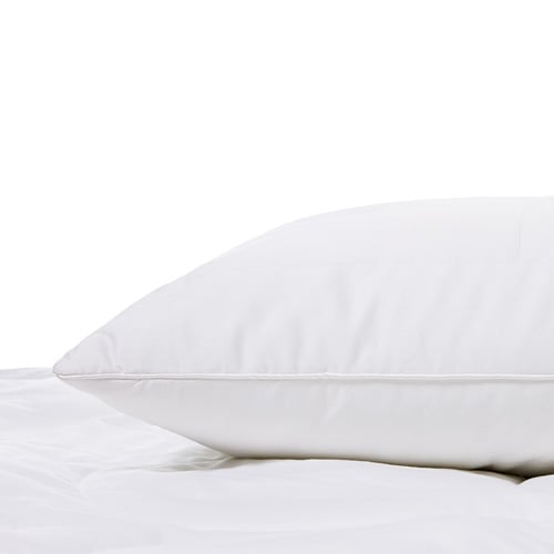 Bamboo pillow resting on top of a mattress with a protector. 