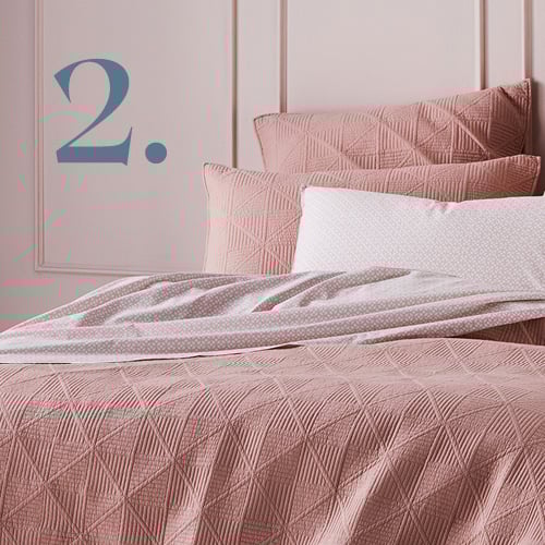 Close-up of Prism Quilted Nude Quilt Cover styled with nude pink printed sheets. 