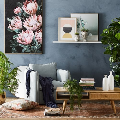 Living room styled with artwork at different heights, armchair, Arden Coffee Table, patterned rug and finished with accessories. 