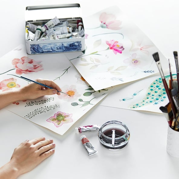 Adairs Design Manager, Bec Jones creating hand painting artwork with paints and brushes around the table