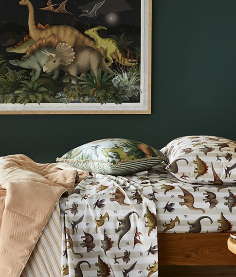 Side-on view of the Fleur Harris Prehistorica Combo Sheet Set with matching wall art in the background. 