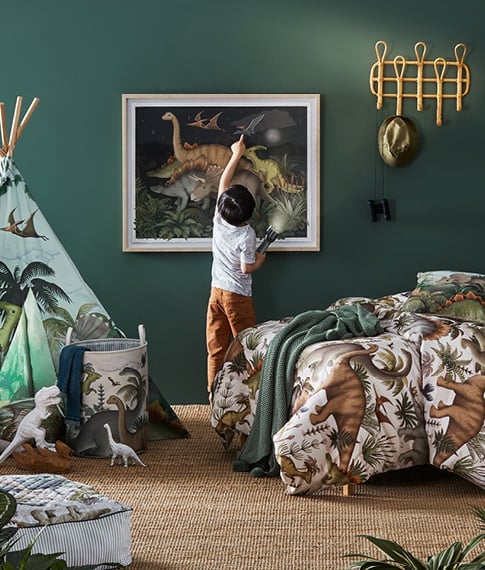 Child pointing at the Fleur Harris Prehistorcia Wall Art in a bedroom styled with matching accessories.  