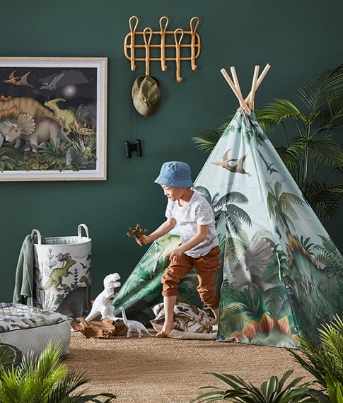 Boy/girl exiting the Fleur Harris Prehistorica Teepee, in the background there’s matching accessories. 