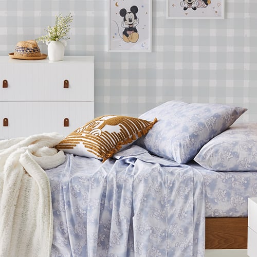kids bed with blue pattern sheet and pillow, mickey mouse canvas displayed on the wall