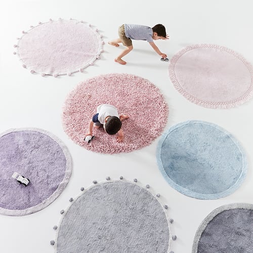 various coloured kids rugs, with two kids playing on them with toy trucks