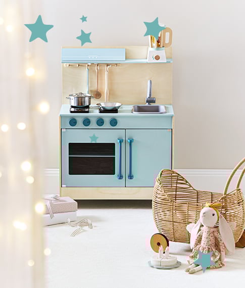 Blue Adairs Kids wooden play kitchen in the background and plush toy in the foreground leaning on a rattan play pram.
