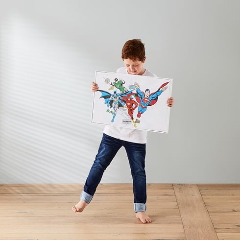 Boy holding Justice League wall art.