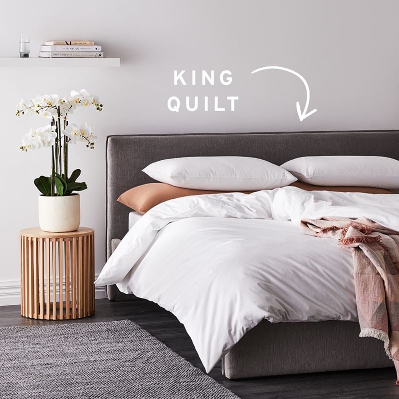 Side-view of bed with white quilt cover and text that reads “King Quilt” with an arrow pointing to the quilt. 