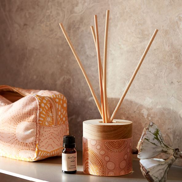 The collection includes homewares such as a reed diffuser with timber lid, the design includes Indigenous artwork from Brad Turner in pink tones.
