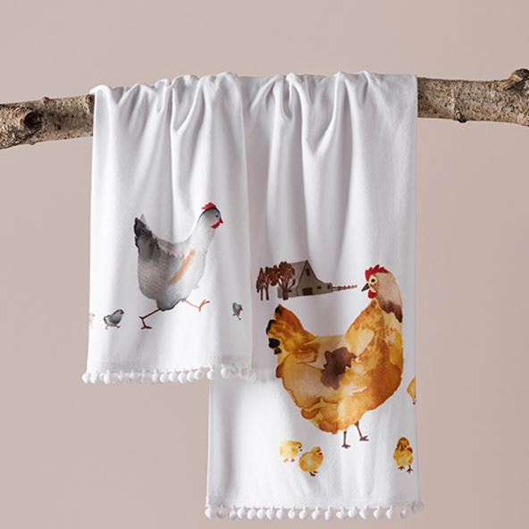 Two Easter Tea Towels featuring watercolour chicken designs, styled hanging off a tree branch. 