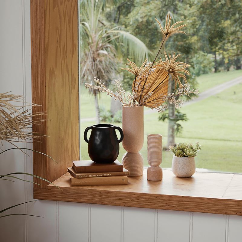 An assortment of small decorative vases arranged in the corner of a large timber window.