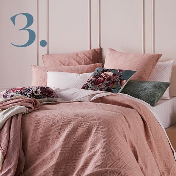 Bed styled with Prism Quilted Nude Quilt Cover, matching pink pillowcases and styled with printed cushions. 