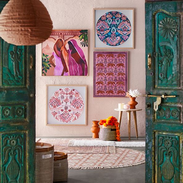 Selection of warm hued wall art framed and hanging on a wall, styled with rugs and table in-front. 