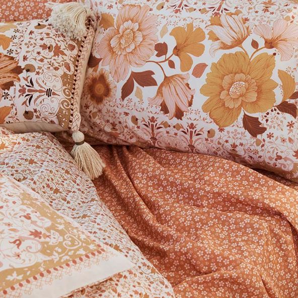 Styled bed with floral designs in orange, rust and pink tones.