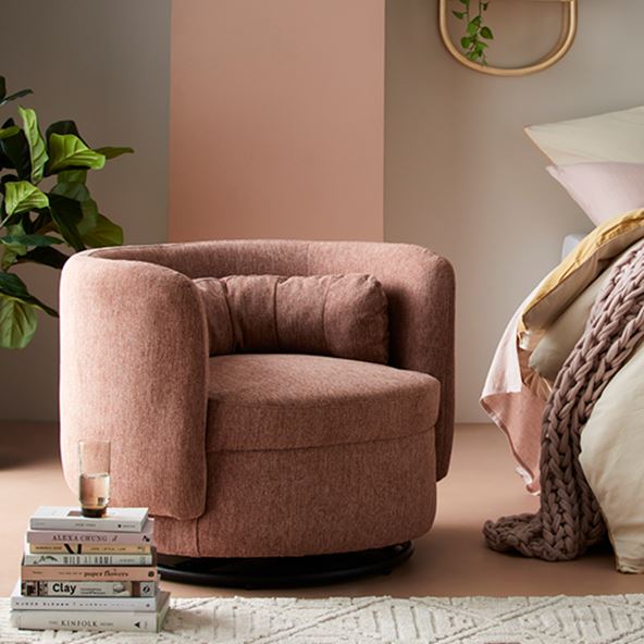Armadale Swivel Chair in pink, pile of books in front with glass on top and bed to the right. 