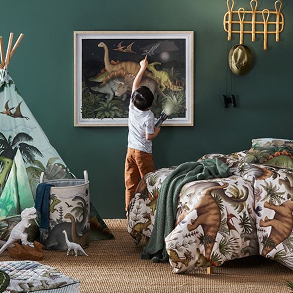 Child pointing at the Fleur Harris Prehistorcia Wall Art in a bedroom styled with matching accessories.  