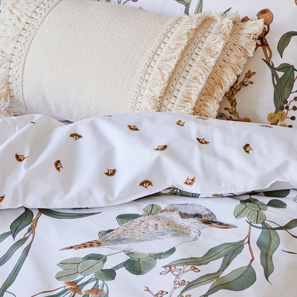 Close-up of botanical bedlinen with neutral tufted cushion. 