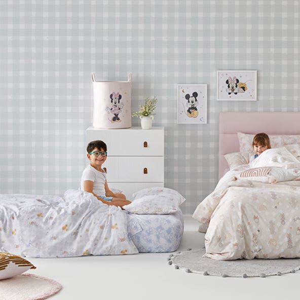 two kids playing in a room with two beds, mickey mouse canvas on the wall