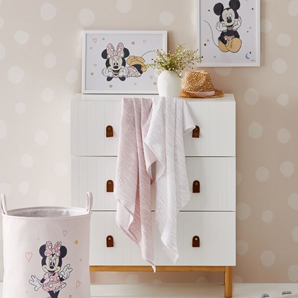 kids room with mickey mouse bag, pink and white towels, mickey mouse canvas on the wall with a white three level drawer
