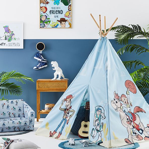 toy story themed kids play area with a kids teepee, foldable plush couch and light brown table, as well as a toy story canvas on the wall
