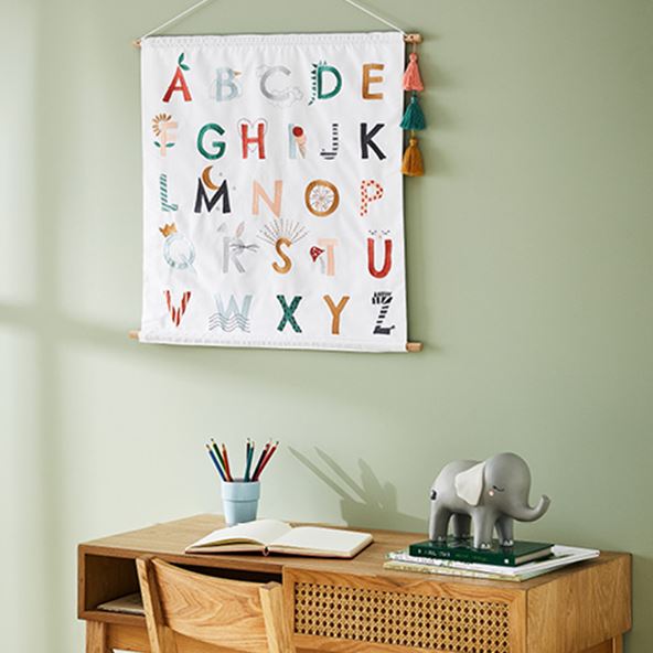 An alphabet wall art chart hanging above a children’s study desk.  